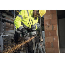 Handwerker mit Metabo Akku-Winkelschleifer trennt Metall auf einer Baustelle, Funkenflug, Schutzkleidung und Helm.
