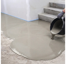 Coulage d'un composé de nivellement liquide à partir d'un seau sur un sol en béton à côté d'un escalier.