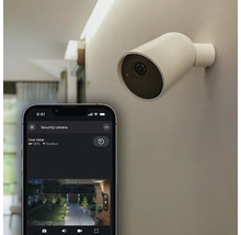 Caméra de surveillance Philips Hue Secure fixée au mur avec smartphone affichant l'image en direct dans l'application Hue.