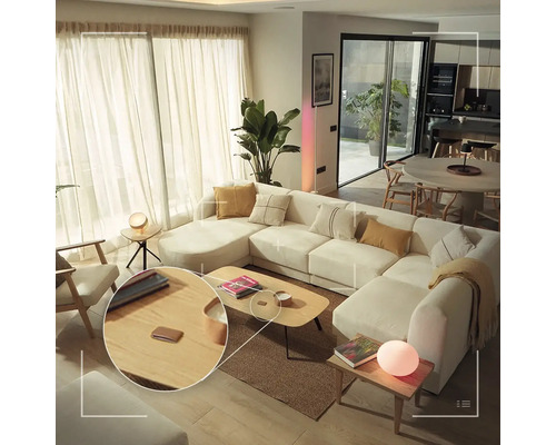 Salon moderne et lumineux avec un grand canapé, une table basse en bois et un interrupteur intelligent pour contrôler la lumière.