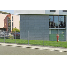 Clôture à doubles fils en métal sur une pelouse devant un bâtiment moderne.