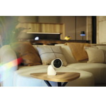 Caméra de surveillance blanche sur une table en bois dans un salon moderne avec canapé.