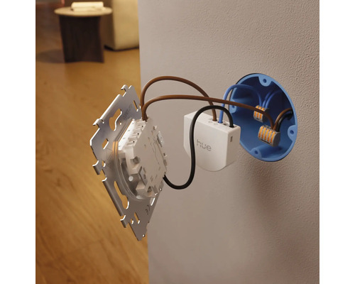 Module d'interrupteur mural Philips Hue avec Philips Hue Logo lors de l'installation dans une boîte d'encastrement avec câblage, bornes et plaque.