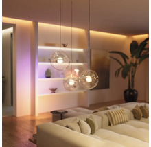 Salon moderne lumineux avec canapé et trois suspensions sphériques Philips Hue en verre suspendues à différentes hauteurs.