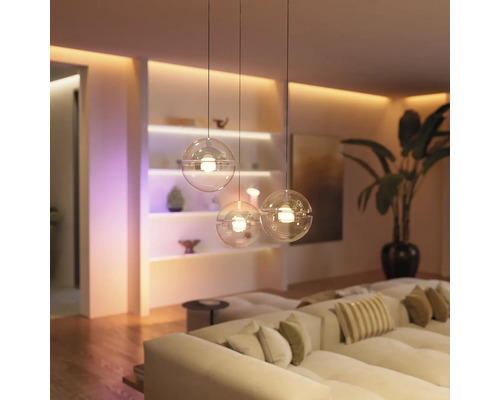 Salon moderne lumineux avec canapé et trois suspensions sphériques Philips Hue en verre suspendues à différentes hauteurs.