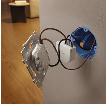 Module d'interrupteur mural Philips Hue lors de l'installation derrière un interrupteur dans une boîte d'encastrement.