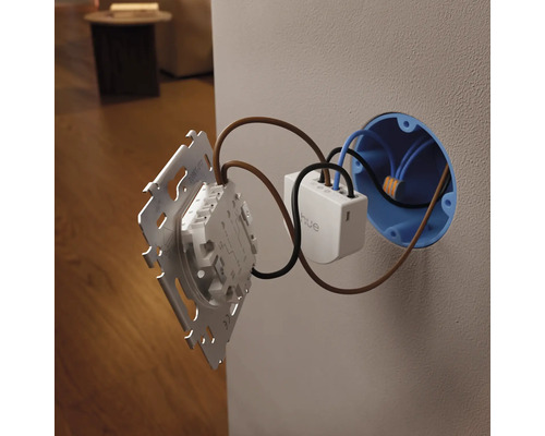 Module d interrupteur mural Philips Hue en cours d installation dans une boîte d encastrement et raccordé à un cadre d interrupteur.
