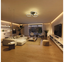 Salon moderne et lumineux avec plafonnier LED en forme d'anneaux, éclairage indirect et suspensions en verre.