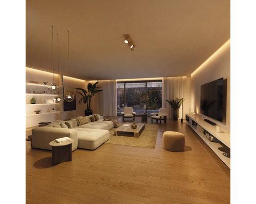 Salon moderne et spacieux avec canapé d'angle clair, table basse en bois, meuble TV et éclairage LED indirect sur un parquet chaleureux.