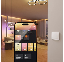 Smartphone avec application pour contrôler l'éclairage intelligent dans un salon moderne avec plafonniers et interrupteur mural.
