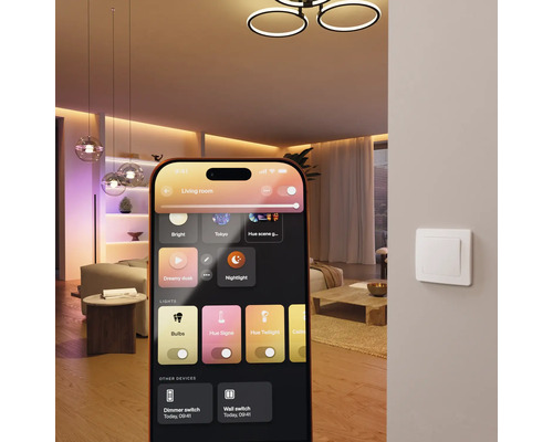 Smartphone avec application pour contrôler l'éclairage intelligent dans un salon moderne avec plafonniers et interrupteur mural.