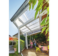 Terrassenüberdachung mit weißem Gestell und lichtdurchlässigen Wellplatten auf einer Holzterrasse in einem Garten mit Kletterpflanzen.