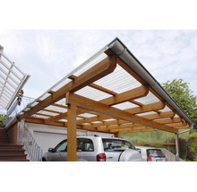 Carport aus Holz mit lichtdurchlässigem Wellplattendach und Dachrinne, an einer Hauswand neben einer Garage montiert.