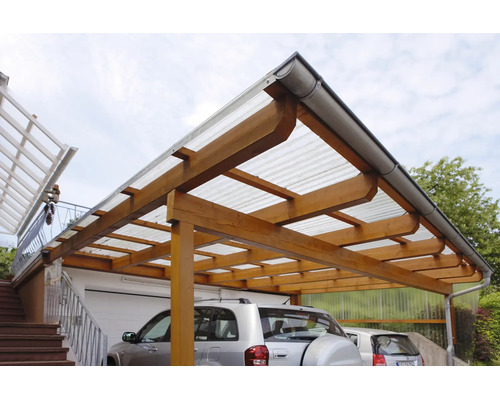 Carport aus Holz mit lichtdurchlässigem Wellplattendach und Dachrinne, an einer Hauswand neben einer Garage montiert.