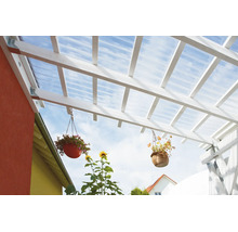 Terrassenüberdachung aus weißem Holz mit transparenten Wellplatten und hängenden Blumenampeln.