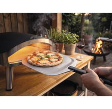 Pizza fraîchement cuite retirée d'un four à pizza portable sur une table en bois dans un jardin avec une pelle à pizza avec Tenneker Logo.