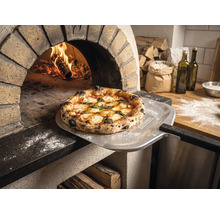 Pizza fraîchement cuite sur une pelle à pizza avec Tenneker Logo devant un four à pierre enflammé dans une cuisine rustique.