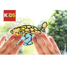 Mains d'enfant touchant un motif de poisson réalisé avec la peinture pour fenêtres Marabu KIDS sur une vitre. Logo Marabu.