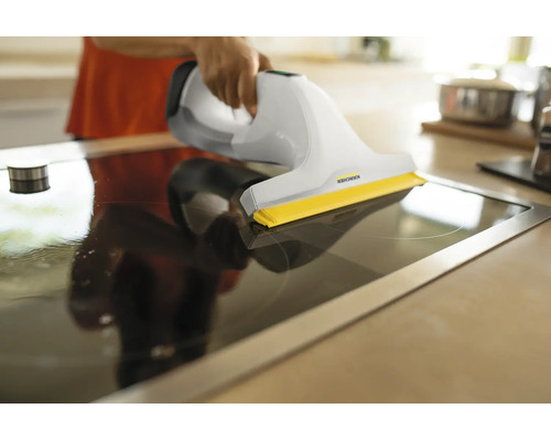 Nettoyeur de vitres Kärcher utilisé pour nettoyer une plaque de cuisson vitrocéramique dans une cuisine.