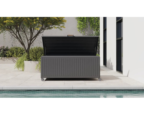 Coffre de jardin moderne en métal gris foncé avec roulettes et couvercle ouvert, sur une terrasse à côté d'une piscine et de plantes.