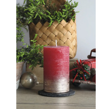 Strukturierte Stumpenkerze in Rot und Gold auf Schieferuntersetzer in weihnachtlicher Szene mit grünen Zweigen und rotem Spielzeug-Lastkraftwagen.