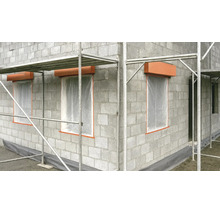 Gros œuvre en blocs de béton avec échafaudage, ouvertures de fenêtres avec film de protection et coffres de volets roulants sur un chantier.