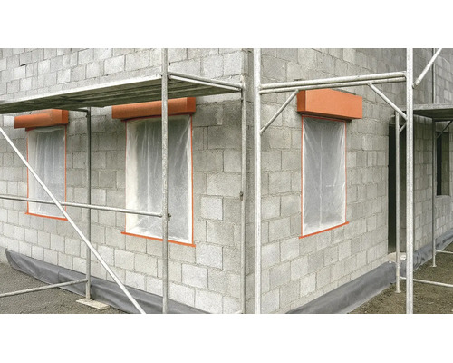 Gros œuvre en blocs de béton avec échafaudage, ouvertures de fenêtres avec film de protection et coffres de volets roulants sur un chantier.