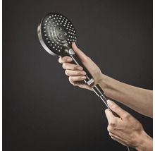 Eine Hand schraubt einen runden Handbrausekopf mit mehreren Düsen auf einen Duschschlauch.