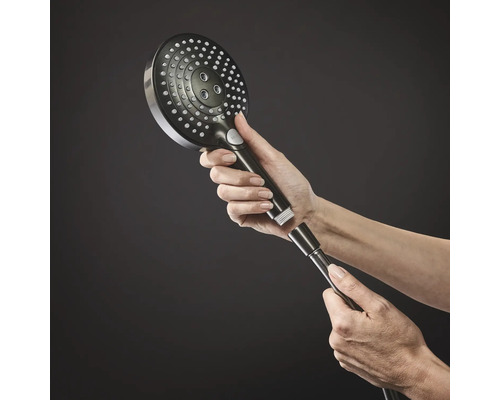 Eine Hand schraubt einen runden Handbrausekopf mit mehreren Düsen auf einen Duschschlauch.