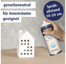 Eine Hand sprüht mit Belton Aqua Sprayfarbe ein weißes Deko Haus. Das Produkt ist geruchsneutral, für Innenräume geeignet und RAL 9010 seidenmatt.
