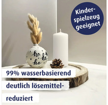 Weihnachtliche Tischdekoration mit einer bemalten Kugel, Stumpenkerze, Zapfen und getrockneten Gräsern auf einer Holzscheibe.