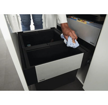 Système de tri des déchets encastrable Blanco dans un meuble de cuisine avec une personne nettoyant le bac avec un chiffon.