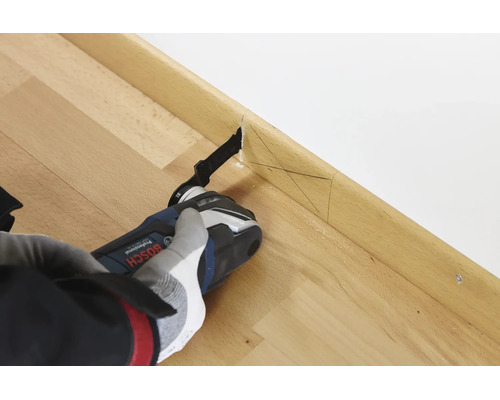 Un outil multifonction Bosch coupant une plinthe en bois avec des marques de mesure