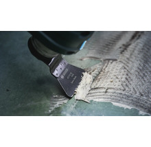 Outil multifonction Bosch avec racloir ATZ 52 SC enlevant les résidus de colle d'une surface.