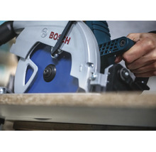 Une scie circulaire Bosch coupant une planche en bois, tenue par une main.