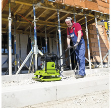 Un ouvrier utilise une plaque vibrante Zipper sur un chantier avec des étais.