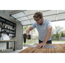 Artisan perçant un trou dans une plaque métallique avec une perceuse sans fil Bosch sur un établi dans un garage.