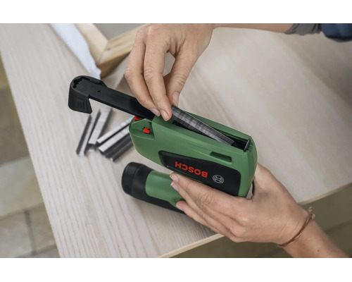 Eine Person legt Metallklammern in das Magazin eines elektrischen Bosch Tackergeräts ein.