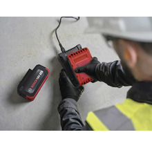Handwerker legt einen 18 Volt Akku in ein Bosch Ladegerät ein, ein weiterer 4 Amperestunden Akku liegt daneben.