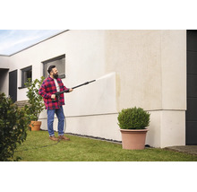 Un homme nettoie le mur extérieur d une maison moderne avec un nettoyeur haute pression.