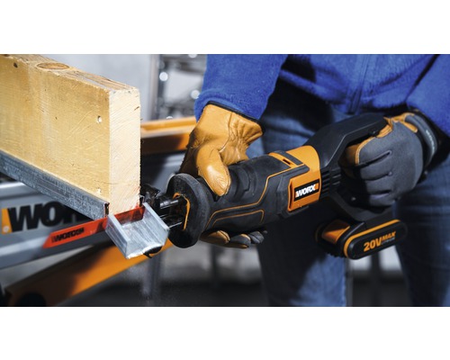 Une personne scie une planche de bois avec une scie sabre sans fil. La scie est de Worx.