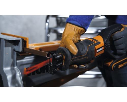 Une personne coupe un tuyau de cuivre avec une scie sabre de Worx.