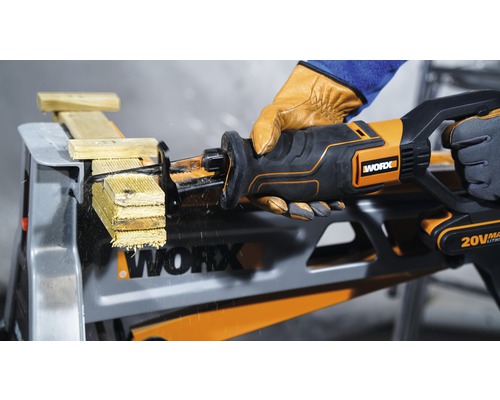 Scie sabre sans fil coupant du bois sur un établi, manipulée par une personne gantée, logo Worx visible.