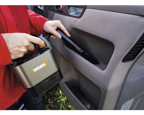 Une personne aspire l''intérieur d''une voiture avec un aspirateur sans fil de la marque Worx