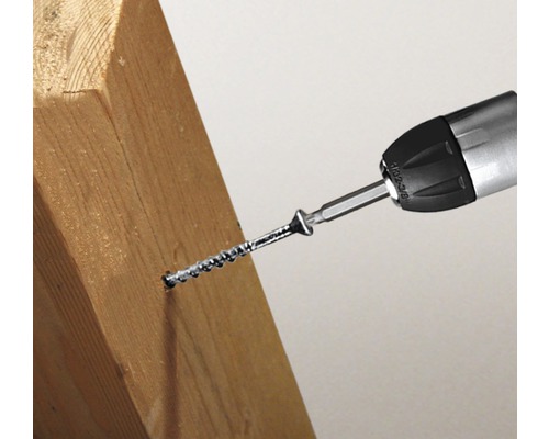 Un tournevis visse une vis dans une pièce de bois