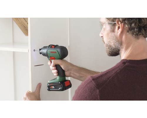 Artisan fixant une étagère avec un tournevis sans fil Bosch