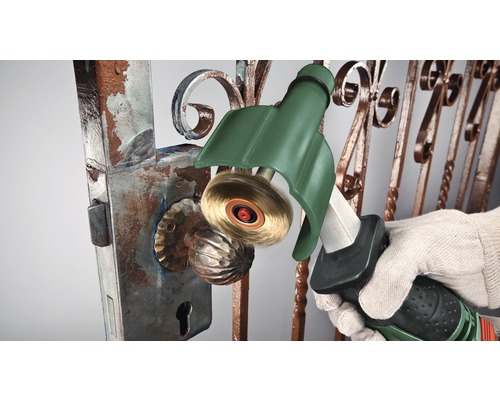 Une personne enlève la rouille d''un portail avec une brosse métallique.