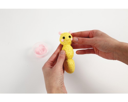 Une personne façonne une chenille en pâte à modeler