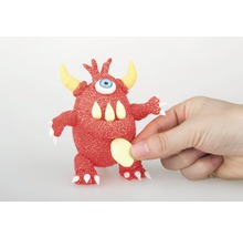 Monstre rouge avec un œil, des cornes et des dents tenu par une main