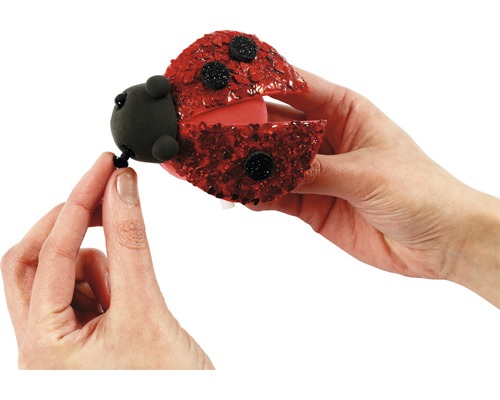 Dekorative Marienkäferfigur wird von einer Hand gehalten.